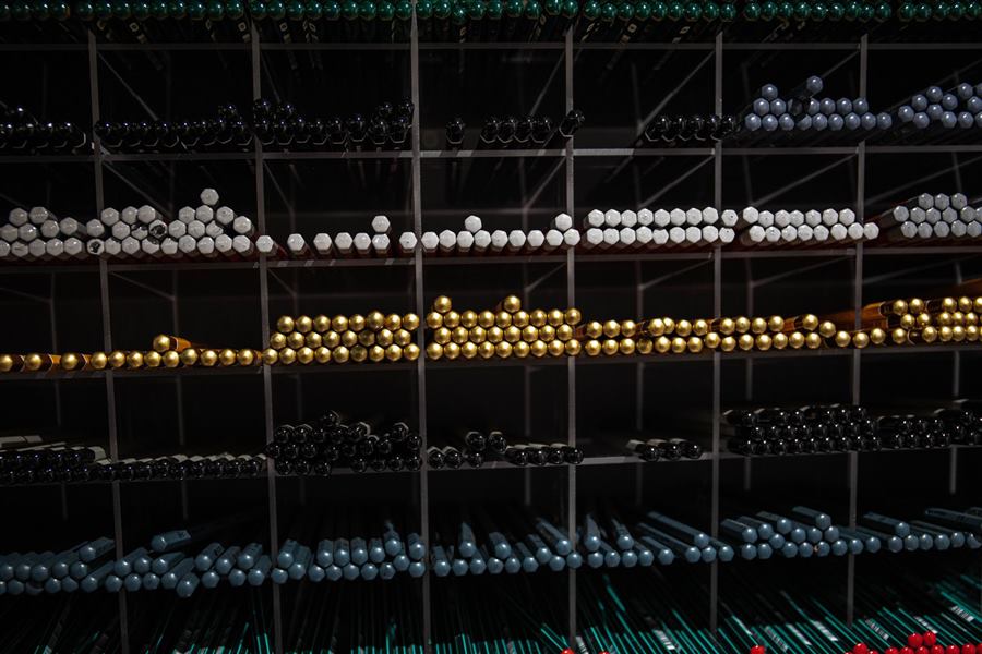 A neatly organized display of colorful pencils arranged on shelves, showcasing a variety o